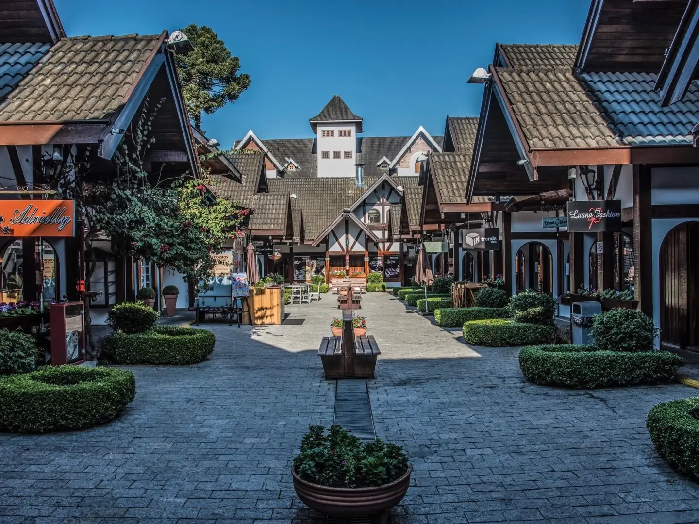 Rua comercial de Campos do Jordão, com arquitetura alpina, lojas e canteiros